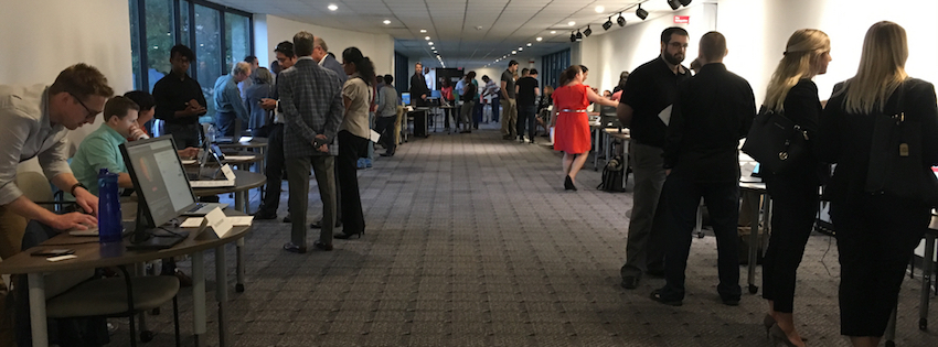 People standing in groups at a conference room.